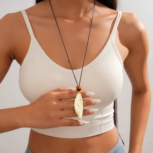 Close-up of leather leaf pendant necklace with gold accents worn by a model