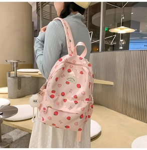 Close-up of pink school backpack with strawberry prints and side storage pockets