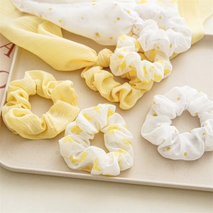 Set of 5 floral chiffon scrunchies with daisy and butterfly prints on a beige tray