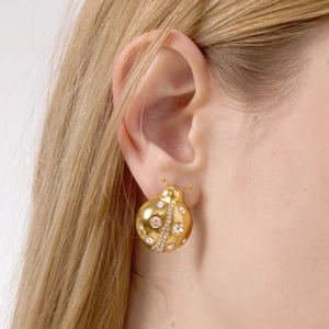 Élégantes boucles d'oreilles coccinelle dorées avec cristaux portées par un mannequin