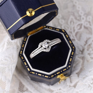 Detail of a heart-shaped diamond ring in a luxury blue velvet box on lace fabric