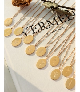 Detailed view of oval floral engraved pendants on gold link chains with vintage style