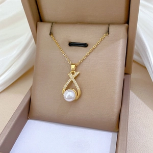 Close-up of titanium necklace featuring a cross pendant with zircon and large pearl detail