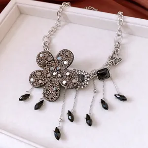 Gros plan sur pendentif fleur argenté avec cristaux sombres et détails à franges