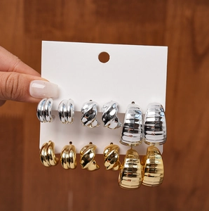 Close-up of six pairs of geometric C-shaped metal stud earrings in gold and silver
