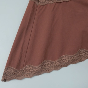 Detail of brown fabric hem featuring intricate floral lace trim and smooth plain weave