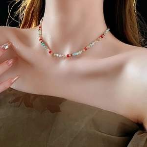 Close-up of colorful beaded necklace with red blue and gold beads on a model's neck