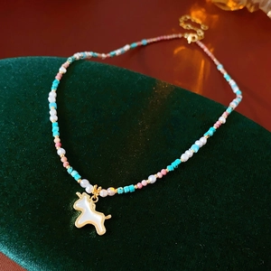 Macro detail of unicorn pendant necklace with colorful beads and gold clasp on velvet