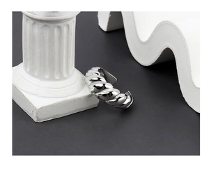 Close-up of a silver croissant style twisted ring resting on a white Roman column