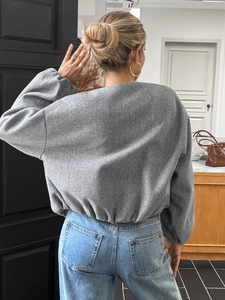Back view of a grey long-sleeved casual jacket with elastic hem on a female model