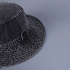 Detailed macro view of dark grey washed denim fabric with precise white stitching details