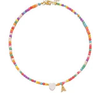 Colorful beaded necklace with white heart and golden letter A charm on white background