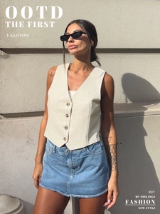 Detail of cream V-neck cotton linen vest with dark buttons and denim skirt with frayed hem