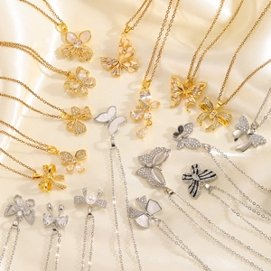 Collection of crystal bow and butterfly necklaces on cream satin background