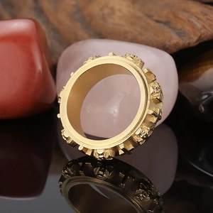 Close-up of golden punk ring featuring detailed skull and cross relief with reflections