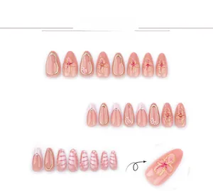 Detail of pink French press-on nails with 3D floral accents and gold trim details