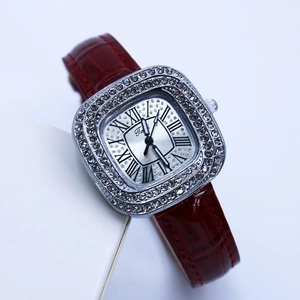 Detail of square silver watch case with rhinestones and red leather crocodile strap