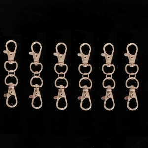 Set of six rose gold swivel lobster clasps for DIY bag accessories on black background