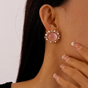 Detail of pink resin flower earring with white pearls and crystals worn on model