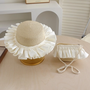 Detail of woven straw sun hat and matching bag with elegant white satin ruffles