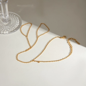 Minimalist gold stainless steel hand chain bracelet with finger ring on white background
