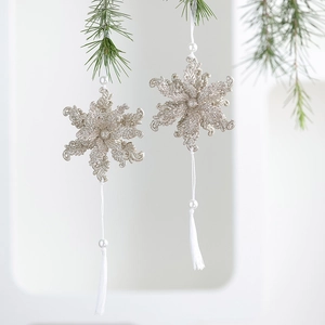Champagne glitter snowflake Christmas ornaments with pearls and tassels on pine branches