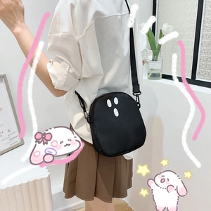 Détail d'un sac bandoulière noir avec imprimé visage de fantôme et sangle réglable
