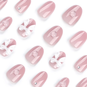 Faux ongles rose poudré avec nœuds blancs, cœurs 3D et strass argentés