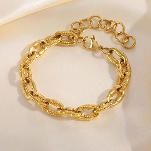 Detailed macro view of gold plated Figaro bracelet with embossed links and lobster clasp