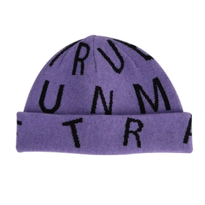 Detail of purple knitted beanie featuring black jacquard letters and soft ribbed texture