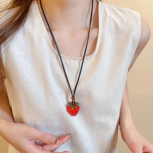 Close-up of strawberry pendant necklace with translucent red resin and green leaves