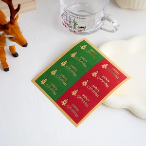 Detailed view of red and green Christmas tree stickers with gold Merry Christmas foil
