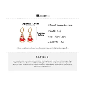 Macro detail of 14k gold plated gourd earrings with red resin and zircon inlay