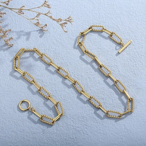 Detail of gold hip-hop chain with twisted links and OT toggle clasp on purple texture