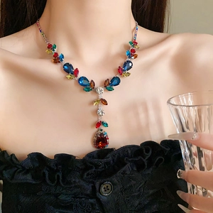 Macro shot of colorful leaf and teardrop crystals on a silver necklace worn by a model