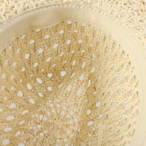 Detail view of woven straw sun hat showing hollow texture and inner sweatband comfort