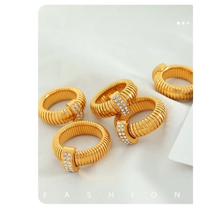 Detail of golden spiral rings with rhinestone inlay on elegant white silk backdrop