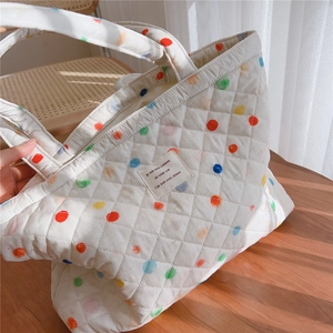 Detail of white quilted tote bag with colorful polka dots and French woven label