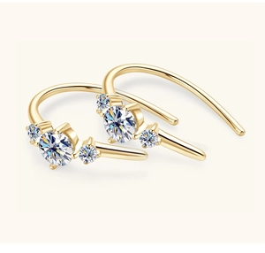 Macro detail of gold S925 silver hook earrings with three round moissanite gemstones