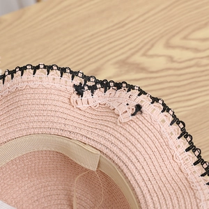 Detailed close-up of pink straw hat with black lace trim and neat inner sweatband