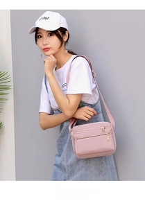 Pink waterproof nylon crossbody bag with three zipper compartments and shoulder strap