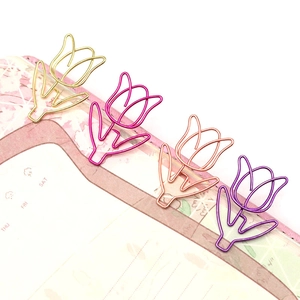 Macro shot of colorful tulip shaped paper clips in gold and purple on notebook pages