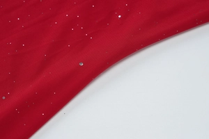 Detail of red mesh fabric with shimmering silver sequins and breathable net texture
