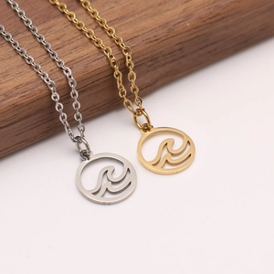 Gros plan de colliers en acier inoxydable or et argent avec pendentifs cercle à vagues
