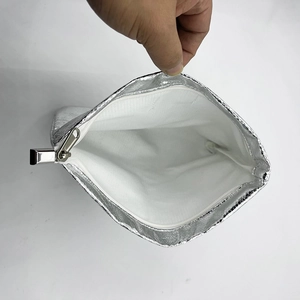 Macro shot of silver textured makeup bag showing white lining and metallic zipper closure