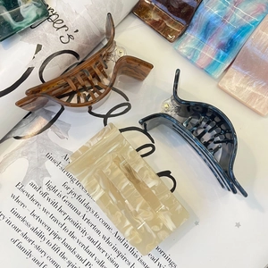 Detail of luxury acetate hair claws in various marbled colors on a magazine background