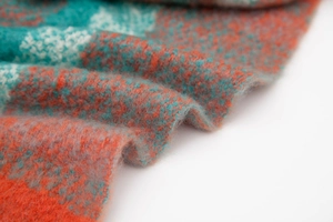 Detailed macro view of orange and teal knit fabric with soft fringe and thick wool texture
