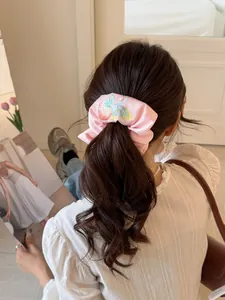 Detailed view of pink satin scrunchie with fruit embroidery on a ponytail