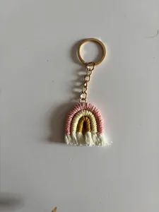 Detail of handmade rainbow keychain with colorful woven rope and white cotton tassels