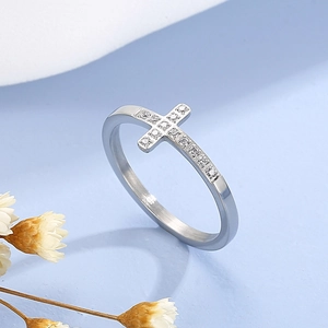Détail d'une bague croix en argent avec oxydes de zirconium sur surface texturée bleue